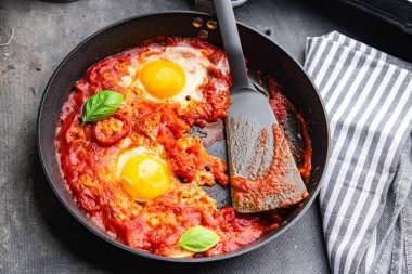 Yumurta kızartılmış domatesli Shakshuk kahvaltı yumurtaları sebze yemeği atıştırmalıkları fotokopi masasının üzerinde.