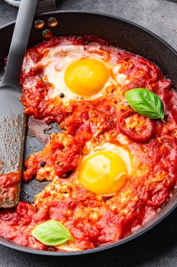 Yumurta kızartılmış domatesli Shakshuk kahvaltı yumurtaları sebze yemeği atıştırmalıkları fotokopi masasının üzerinde.