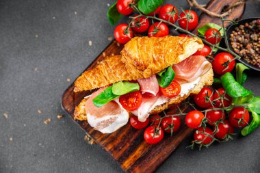 croissant sandwich ham, tomato, green leaves salad fast food Takeaway healthy meal food snack on the table copy space food background rustic top view