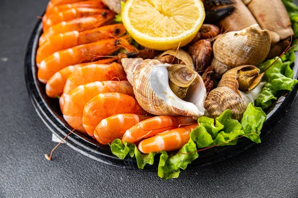 seafood plate assorted shrimps, crab claws, clams, rapan, trumpeter mollusk Takeaway healthy meal food snack on the table copy space food background rustic top view