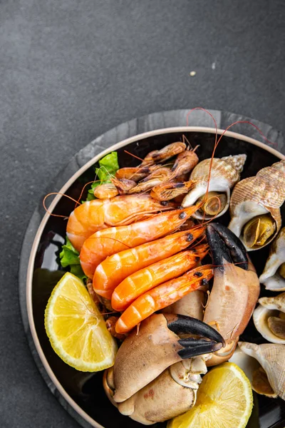 seafood plate assorted shrimps, crab claws, clams, rapan, trumpeter mollusk Takeaway healthy meal food snack on the table copy space food background rustic top view