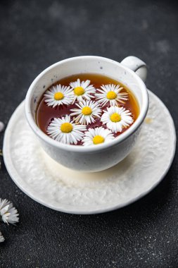 Çay, papatya çiçekleri sıcak içecek, sağlıklı yemek atıştırmalıkları masanın üzerinde fotokopi, arka plan kırsal manzarası.