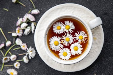 Çay, papatya çiçekleri sıcak içecek, sağlıklı yemek atıştırmalıkları masanın üzerinde fotokopi, arka plan kırsal manzarası.