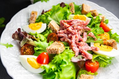 Et salatası, pastırma, yumurta, kızarmış ekmek, marul, salata soslu vinaigrette Vosges salatası Lorraine mutfağı yemek atıştırmalığı masa üzerinde fotokopi uzay yemeği arka plan kırsal manzarası