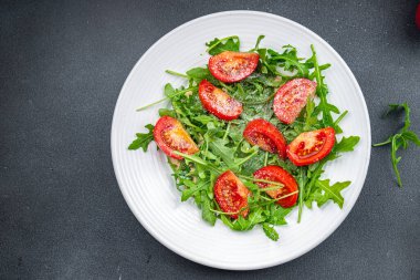 Bir tabak salata, domates, roka, rendelenmiş peynir, zeytinyağı sağlıklı yemek aperatifleri fotokopi masasında uzay yiyecekleri arka plan kırsal üst görüş keto veya paleo diyeti vejetaryen veya vejetaryen yemeği yok. 