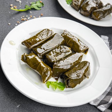 Dolma üzümleri et delerken sağlıklı yemek atıştırmalıklarını fotokopi masasına bırakır. Arka plandaki yiyeceklerin kırsal manzarası.