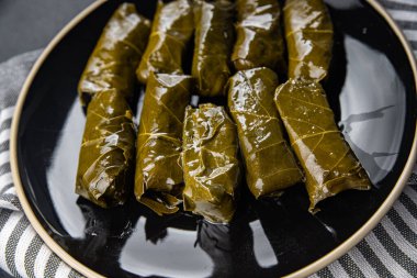 Dolma üzümleri et delerken sağlıklı yemek atıştırmalıklarını fotokopi masasına bırakır. Arka plandaki yiyeceklerin kırsal manzarası.