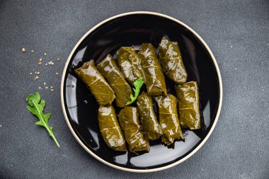 Dolma üzümleri et delerken sağlıklı yemek atıştırmalıklarını fotokopi masasına bırakır. Arka plandaki yiyeceklerin kırsal manzarası.
