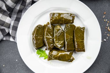 Dolma üzümleri et delerken sağlıklı yemek atıştırmalıklarını fotokopi masasına bırakır. Arka plandaki yiyeceklerin kırsal manzarası.