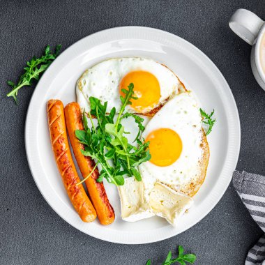 Kızarmış yumurta sosisi kahvaltı yeşil yapraklar marul roka yemek abur cuburu masada fotokopi uzay yemeği arka plan kırsal üst görünüm