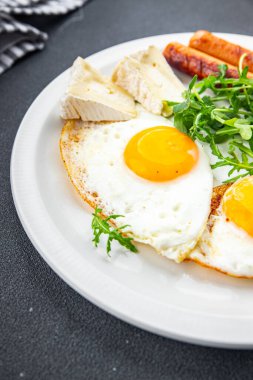 Kızarmış yumurta sosisi kahvaltı yeşil yapraklar marul roka yemek abur cuburu masada fotokopi uzay yemeği arka plan kırsal üst görünüm