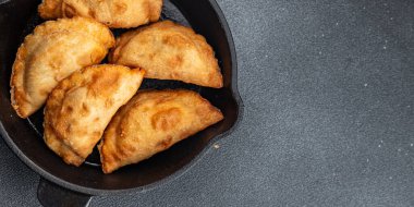 Empanada 'nın sığır eti eti. Masanın üstüne tıkıştırılmış yiyecek. Arka plandaki yiyeceklerin fotokopisi.