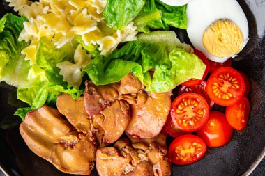 Tavuk ciğeri salatası domates, yeşil yaprak marulu, haşlanmış yumurta, farfalle makarna salatası sağlıklı yemek atıştırmalıkları yemek için hazır sofrada fotokopi uzayı arka plan kırsal manzarası