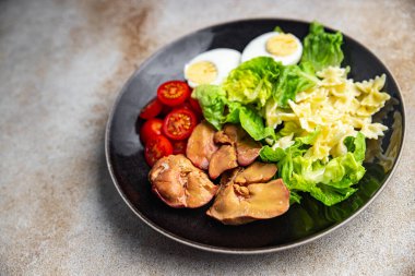 Tavuk ciğeri salatası domates, yeşil yaprak marulu, haşlanmış yumurta, farfalle makarna salatası sağlıklı yemek atıştırmalıkları yemek için hazır sofrada fotokopi uzayı arka plan kırsal manzarası