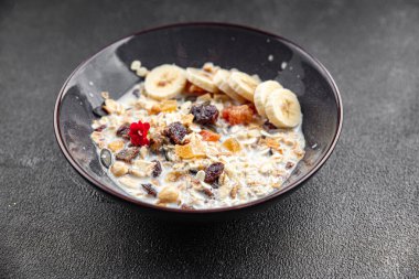 Sütlü, kurutulmuş meyve ve taze muz aromalı kahvaltı. Masanın üzerinde sağlıklı yemek atıştırmalıkları yemek için hazır. Arka plan fotokopisi, kırsal üst görüş, keto veya paleo diyeti.