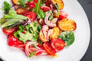 Salata, patates, sebze, patates, domates, soğan, yeşil salata yaprakları, salata sosu, salata sosu, salata soslu sebzeler, masada sağlıklı yemek atıştırmalıkları fotokopi uzayı arka plan kırsal manzarası. 