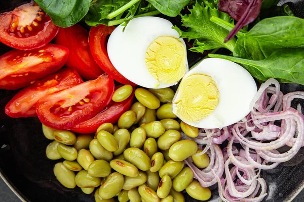 edamame bean salad vegetables, tomato, boiled egg, salad dressing ready to eat healthy appetizer meal food snack on the table copy space food background rustic top view keto or paleo diet vegetarian vegan food no met