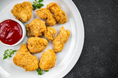 Tavuklu nugget bol yağda kızartılmış domates soslu et. Yemek için hazır. Masada atıştırmalık.