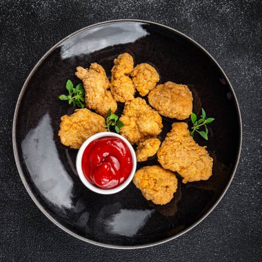 Tavuklu nugget bol yağda kızartılmış domates soslu et. Yemek için hazır. Masada atıştırmalık.