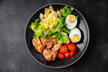 Salata tavuk ciğeri, makarna, domates, yeşil yaprak marul, haşlanmış yumurta, farfalla atıştırmalık yemek masada fotokopi uzayı arka plan kırsal manzarası