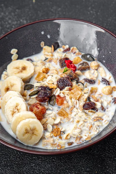 fresh granola bowl milk, dried fruit and banana tasty breakfast meal food snack on the table copy space food background rustic top view
