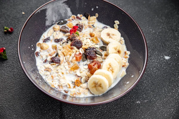 fresh granola bowl milk, dried fruit and banana tasty breakfast meal food snack on the table copy space food background rustic top view