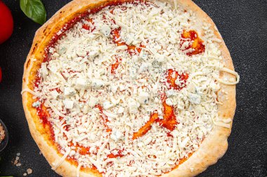 Çiğ pizza dört çeşit akmezan peyniri, gorgonzola, mozzarella, hazır aperatif aperatifler masada.