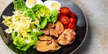 Salata tavuk ciğeri, makarna salatası, domates, yeşil yaprak marul, haşlanmış yumurta, farfalla atıştırmalık yemek masada fotokopi uzayı arka plan kırsal manzarası