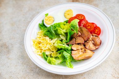 Salata tavuk ciğeri, makarna salatası, domates, yeşil yaprak marul, haşlanmış yumurta, farfalla atıştırmalık yemek masada fotokopi uzayı arka plan kırsal manzarası