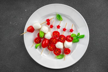Caprese canaps mozzarella ve domates aperatifli salata şiş parmaklı, lezzetli, sağlıklı yemek aperatifli aperatifler masa üzerinde fotokopi uzay yiyecekleri arka plan kırsal üst görünüm keto veya paleo diyeti 