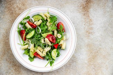 makarna salatası fusilli makarna, salatalık, domates, yeşil marul, soğan yiyen yemek aperatifleri fotokopi masasında.