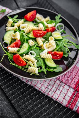 makarna salatası fusilli makarna, salatalık, domates, yeşil marul, soğan yiyen yemek aperatifleri fotokopi masasında.