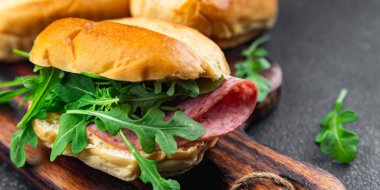 Sandviç ekmeği, sosis, salam, roka, yeşil marul yemek için hazır aperatif yemek atıştırmalıkları fotokopi masasında.