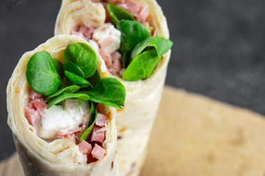 Tortilla dürümü jambon, sebze, peynir, marul lezzetli taze lezzetli sağlıklı yemek iştah açıcı yemek aperatifleri fotokopi masasında uzay yemeği arka plan kırsal manzarası