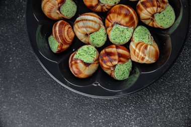 Yeşil yağlı, aromalı salyangozlar lezzetli, sağlıklı, iştah açıcı, yemek aperatifleri fotokopi masasında. Arka plan, kırsal arka plan, üst görüş, keto veya paleo diyeti.