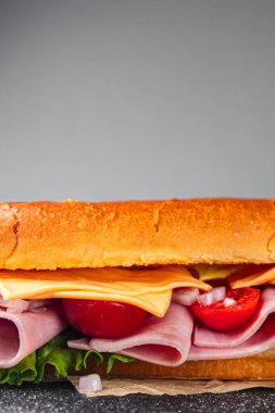 jambonlu sandviç, peynirli, marullu, domatesli, sebzeli, çörekli, çörekli taze yemek. Masada atıştırmalık şeyler yemek.