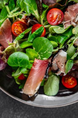 Jamon salatası yeşil yaprak marul, domates, salata sosu aperatif yemek atıştırmalığı fotokopi masasında uzay yemeği arka plan kırsal üst görünüm keto veya paleo diyeti