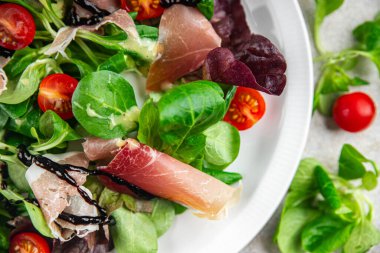 Jamon salatası yeşil yaprak marul, domates, salata sosu aperatif yemek atıştırmalığı fotokopi masasında uzay yemeği arka plan kırsal üst görünüm keto veya paleo diyeti