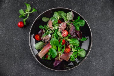 Jamon salatası yeşil yaprak marul, domates, salata sosu aperatif yemek atıştırmalığı fotokopi masasında uzay yemeği arka plan kırsal üst görünüm keto veya paleo diyeti