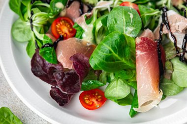 Jamon salatası yeşil yaprak marul, domates, salata sosu aperatif yemek atıştırmalığı fotokopi masasında uzay yemeği arka plan kırsal üst görünüm keto veya paleo diyeti
