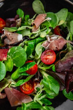 Jamon salatası yeşil yaprak marul, domates, salata sosu aperatif yemek atıştırmalığı fotokopi masasında uzay yemeği arka plan kırsal üst görünüm keto veya paleo diyeti