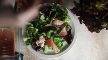 Jamon salatası yeşil yaprak marul, domates, salata sosu aperatif yemek atıştırmalığı fotokopi masasında uzay yemeği arka plan kırsal üst görünüm keto veya paleo diyeti