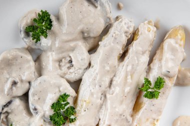 Beyaz krema soslu kuşkonmaz. Masada taze yiyecek. Arka plandaki uzay yiyeceklerinin fotokopisi.