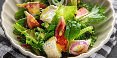 Salata, incir, yeşil marul, incir, yumuşak peynirli atıştırmalık masada fotokopi, uzay yemeği arka plan, kırsal manzaralı vejetaryen yemeği.