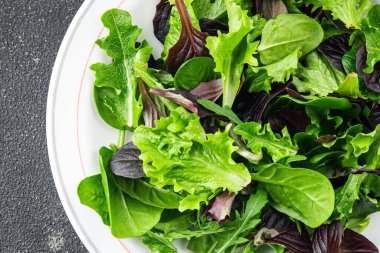 Sağlıklı salata yaprakları karışık salata sulu çerez sebzeler, roka, marul, meşe yaprağı, yeşil yaprak salatası taze yemek arkaplanı masadaki kırsal yiyecekler üst görünüm vejetaryen ve vejetaryen