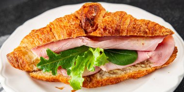 Kruvasan sandviçi, jambon, peynir, yeşil yaprak salatası lezzetli gurme yemek arkaplanı masa kırsal yiyeceklerin üst görünümü fotokopi alanı