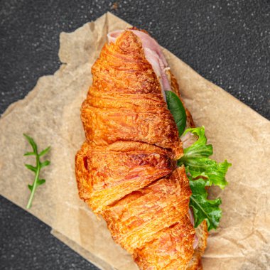 Kruvasan sandviçi, jambon, peynir, yeşil yaprak salatası lezzetli gurme yemek arkaplanı masa kırsal yiyeceklerin üst görünümü fotokopi alanı