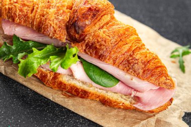 Kruvasan sandviçi, jambon, peynir, yeşil yaprak salatası lezzetli gurme yemek arkaplanı masa kırsal yiyeceklerin üst görünümü fotokopi alanı