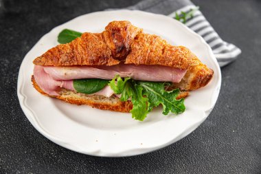 Kruvasan sandviçi, jambon, peynir, yeşil yaprak salatası lezzetli gurme yemek arkaplanı masa kırsal yiyeceklerin üst görünümü fotokopi alanı