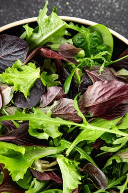 Sağlıklı salata yaprakları karışık salata sulu çerez sebzeler, roka, marul, meşe yaprağı, yeşil yaprak salatası taze yemek arkaplanı masadaki kırsal yiyecekler üst görünüm vejetaryen ve vejetaryen